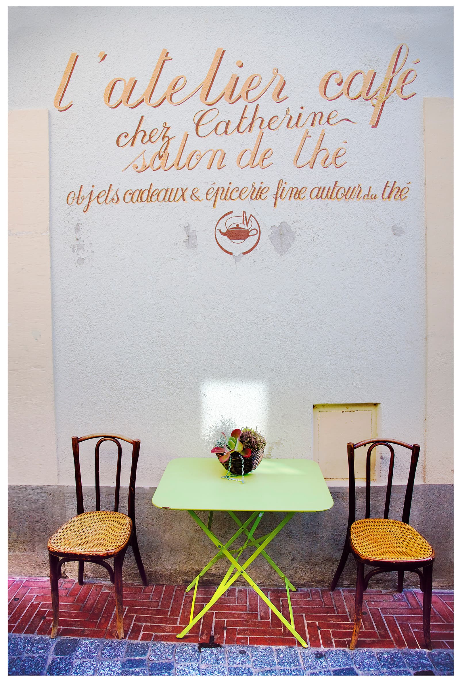 Café tables and chairs beneath hand-painted signage, Provence