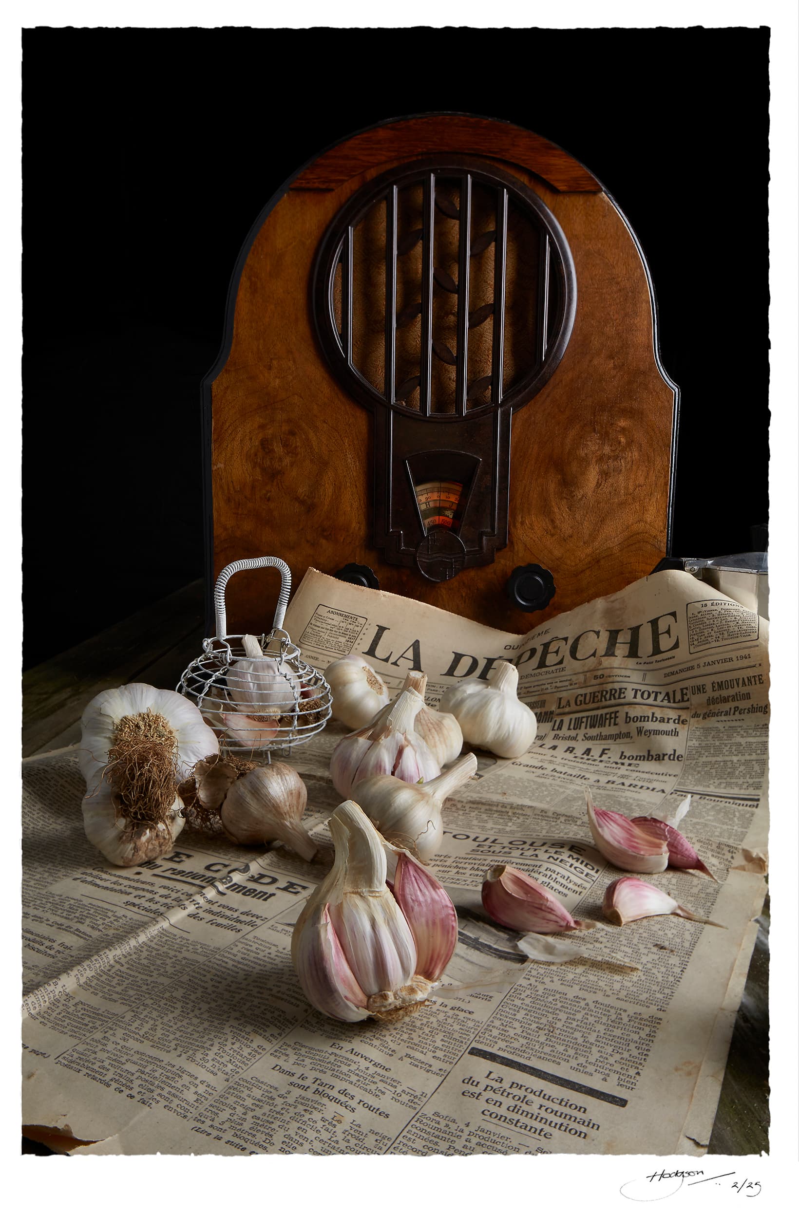 Still life of garlic bulbs and a vintage radio on a 1941 French newspaper, La Dépêche, with wartime headlines