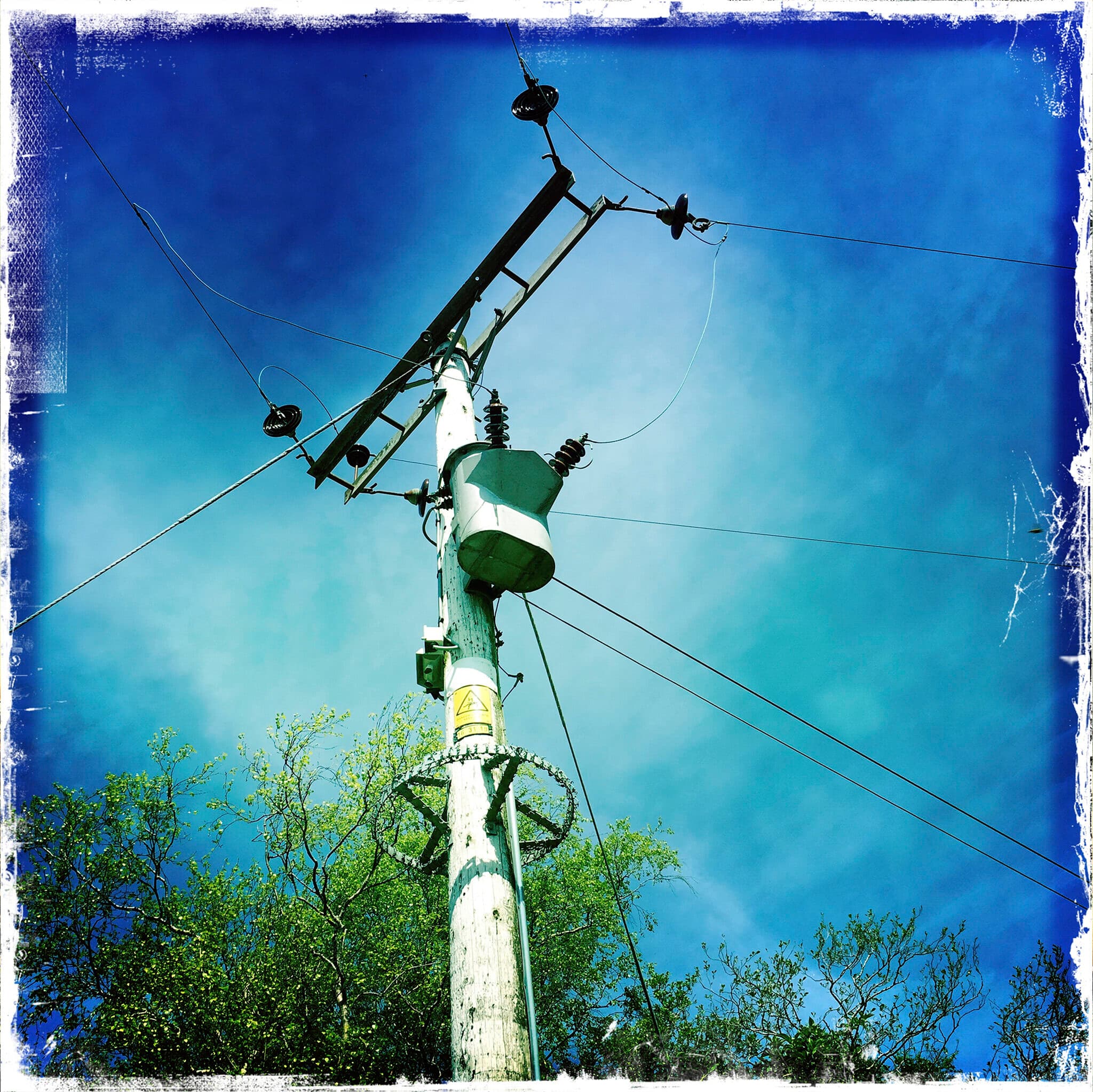 Electricity pole and wires against a blue sky, iPhone