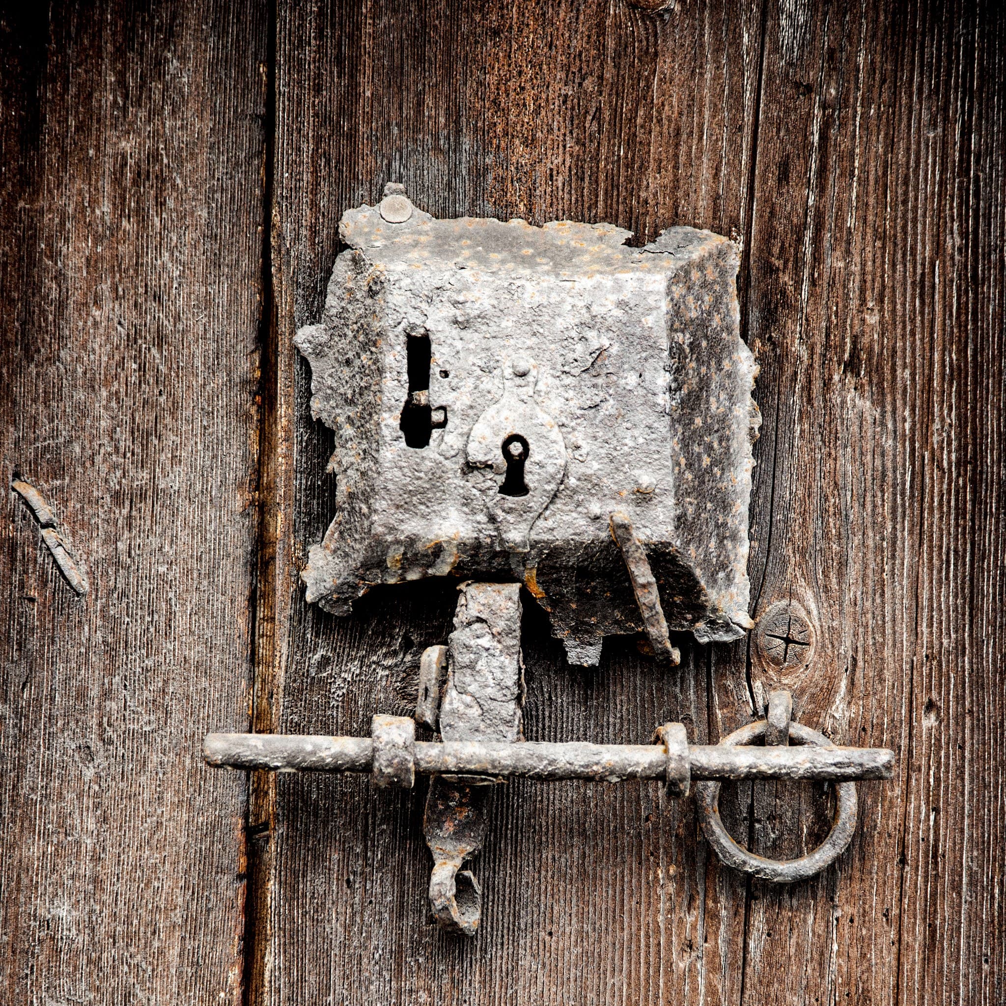 Weathered iron lock plate and bolt latch on an old wooden French door